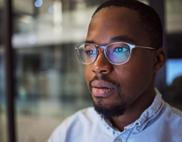 Information technology businessman with glasses and computer reflection for night vision, eyes healthcare, wellness or innovation. Office black man programmer reading online code software development