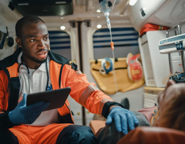 EMS Paramedic in an ambulance Using Tablet with patient